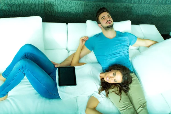 Jeune couple utilisant une tablette PC ensemble sur le canapé à la maison — Photo