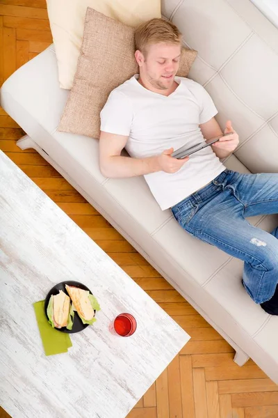 Ung man med en Tablet Pc i soffan — Stockfoto