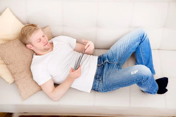 Young man with a Tablet PC on the Sofa — Stock Photo, Image