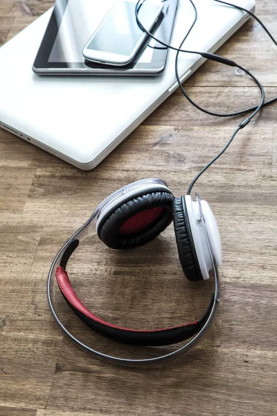 Dispositivos digitales y auriculares en un escritorio de madera —  Fotos de Stock