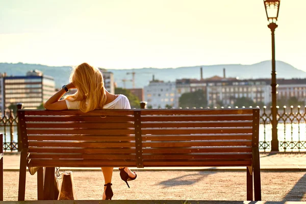 Young woman siting on a bench on the riverside — Stock Photo, Image