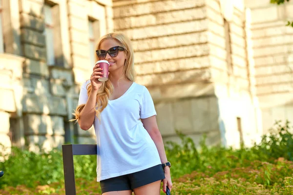 Mujer joven tomando un café frente a un edificio viejo — Foto de Stock