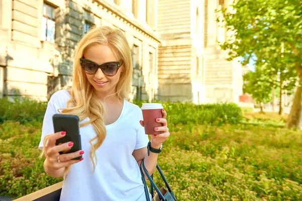 Młoda kobieta na kawę i za pomocą jej telefon — Zdjęcie stockowe