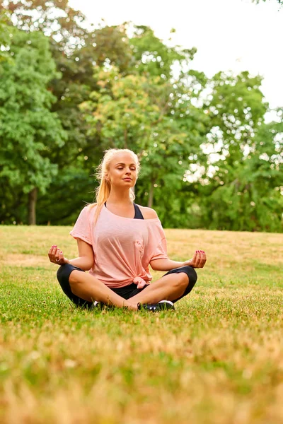 Mujer joven meditando en un campo en un parque — Foto de Stock