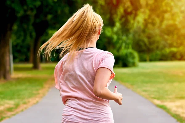 La schiena di una donna in corsa in un parco — Foto Stock
