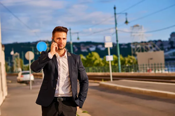 Giovane uomo d'affari che cammina per strada e parla al telefono — Foto Stock