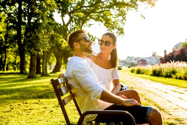 Mooie jonge paar ontspannen op een zonnige zomerdag op een bankje — Stockfoto