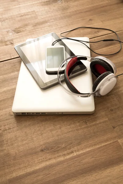Dispositivos digitales y auriculares en un escritorio de madera —  Fotos de Stock