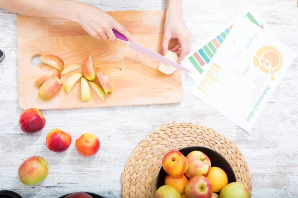 Cutting apple while getting online information about nutrition — Stock Photo, Image