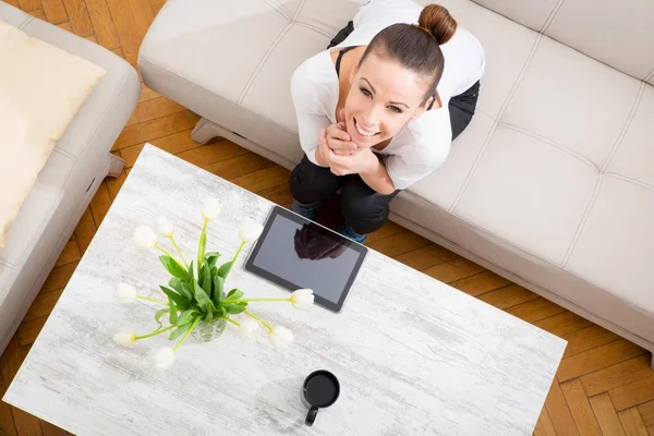 Jeune femme avec une tablette PC sur le canapé — Photo