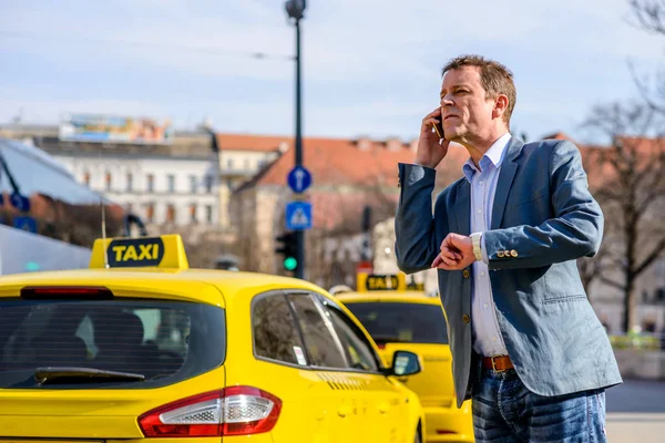 Een zakenman van middelbare leeftijd bij taxi station — Stockfoto