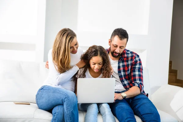 Familia joven sentada en el sofá — Foto de Stock