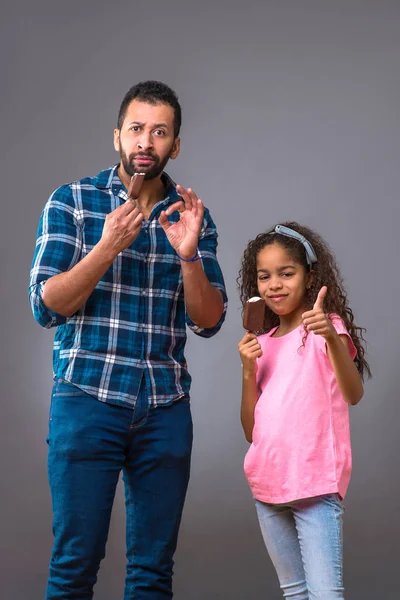 Zwarte vader en zijn dochter eten van consumptie-ijs — Stockfoto