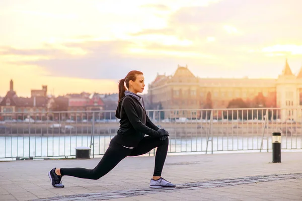 En sportig ung kvinna stretching i solnedgången — Stockfoto