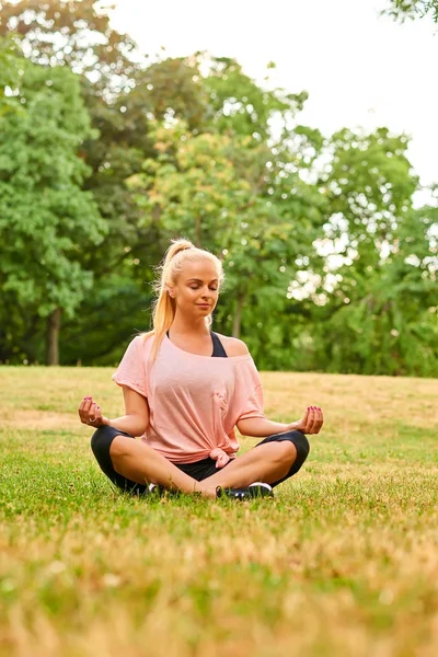 Jovem mulher meditando em um campo em um parque — Fotografia de Stock