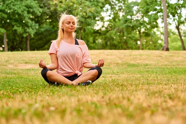 Jonge vrouw mediteren op een veld in een park — Stockfoto