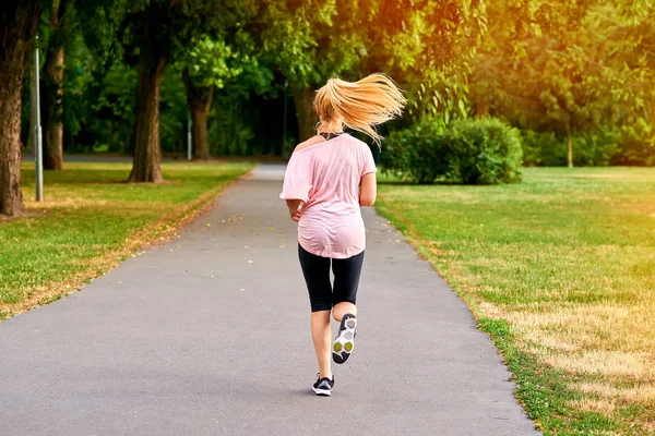 Νεαρή γυναίκα τρέχει μακριά στο δρόμο σε ένα πάρκο — Φωτογραφία Αρχείου