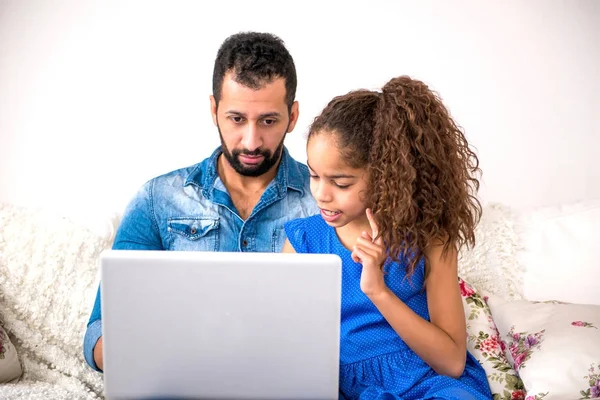 Preto pai e sua filha sentados em um sofá com um laptop — Fotografia de Stock