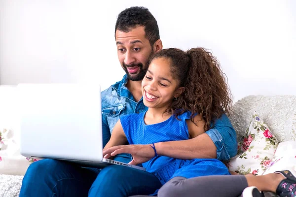 Padre negro y su hija sentados en un sofá con un ordenador portátil — Foto de Stock