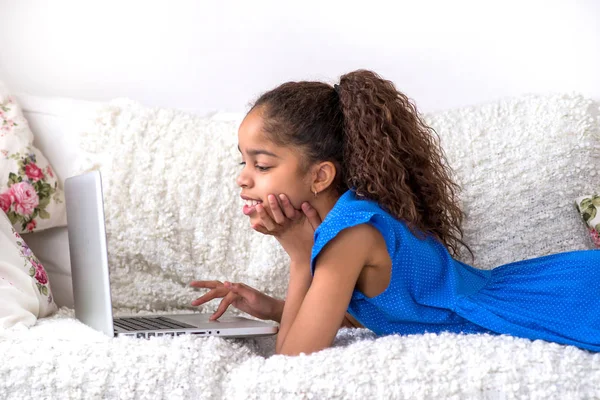 Zwarte tienermeisje aanbrengen op een bank met een laptop — Stockfoto