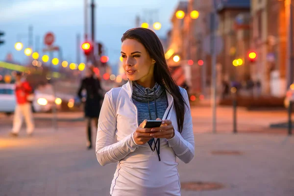 Ung kvinna på gatan med en telefon — Stockfoto