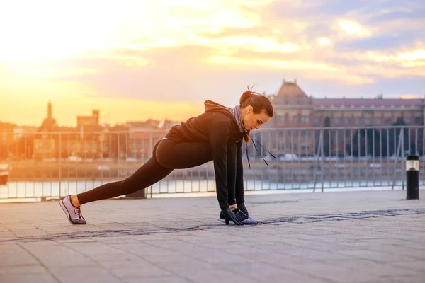 En sportig ung kvinna stretching i solnedgången — Stockfoto