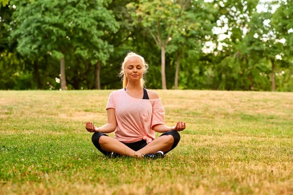 Jonge vrouw mediteren op een veld in een park — Stockfoto