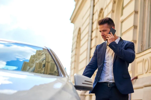 Młody biznesmen, chodzenie do swojego samochodu i rozmawia przez telefon — Zdjęcie stockowe