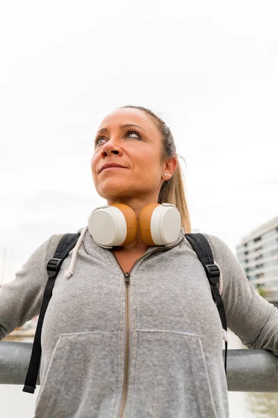 En atletisk kvinna vilar och lutar sig mot bron räcke — Stockfoto