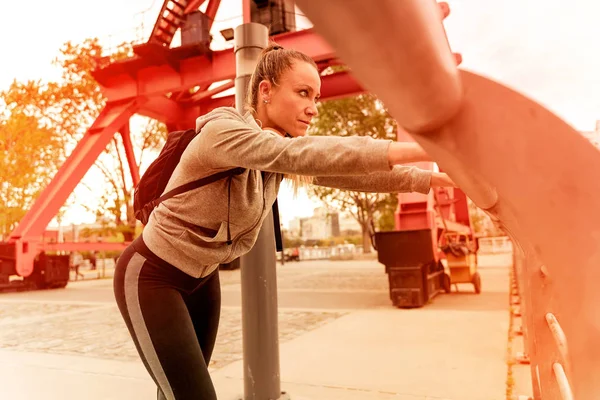 En atletisk kvinna vilar och lutar sig mot bron räcke — Stockfoto