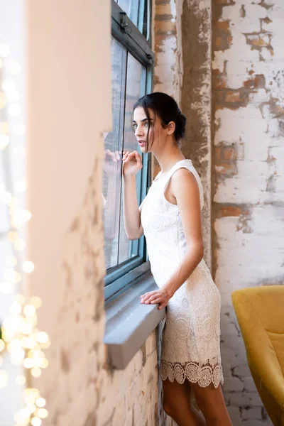 Porträt einer schönen jungen Frau, die am Fenster steht — Stockfoto