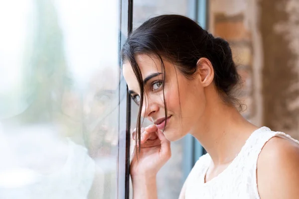 Retrato de uma bela jovem de pé em uma janela — Fotografia de Stock