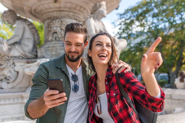 Um casal descobrindo a cidade com um mapa em seu celular . — Fotografia de Stock