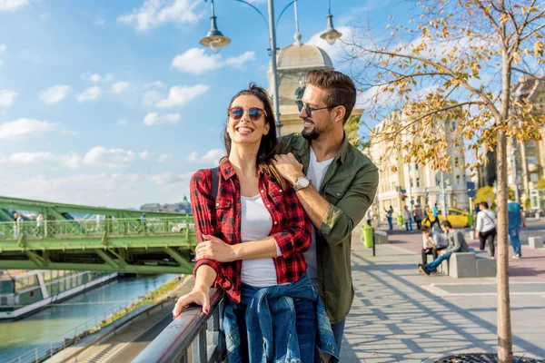 Egy pár, akik élvezik a napsütéses napot a Szabadság híd előtt Budapesten — Stock Fotó