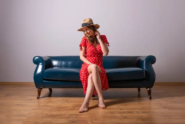 En kvinna i röd klänning sitter på en soffa — Stockfoto