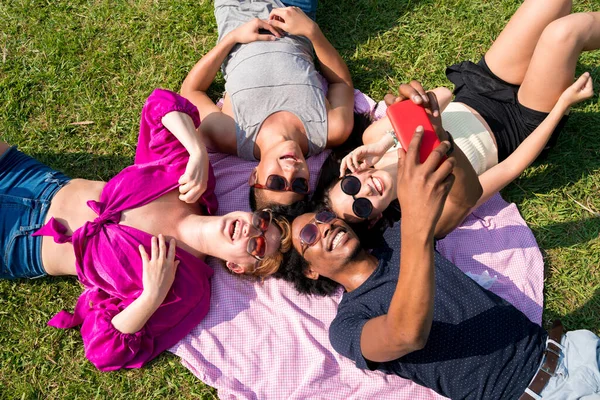 Amigos tomando selfies enquanto deitado na grama — Fotografia de Stock