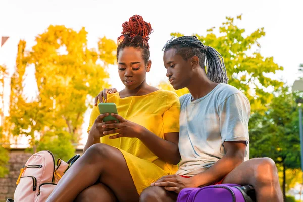 Um casal viajante em um parque verificando um aplicativo em um smartphone — Fotografia de Stock