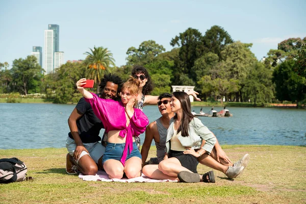 En dykare grupp vänner som tar selfies i en park under sommaren — Stockfoto