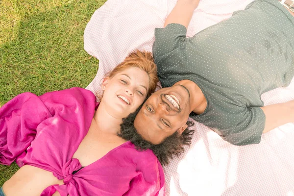 Um jovem casal deitado junto na grama . — Fotografia de Stock