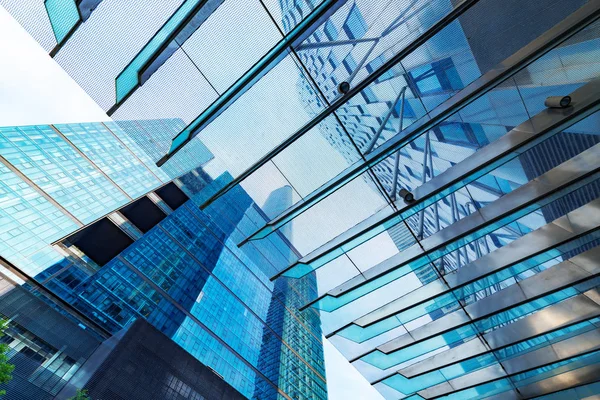 Vista inferior de rascacielos modernos en el distrito de negocios contra el cielo azul —  Fotos de Stock