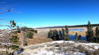Yellowstone Nehri Hayden Vadisi 'nde sonbaharda. Hafif kar tozu. Kamera soldan sağa dönüyor.