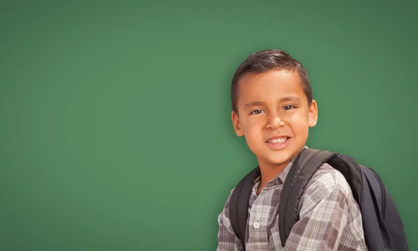 Bonito menino hispânico na frente da placa de giz em branco — Fotografia de Stock