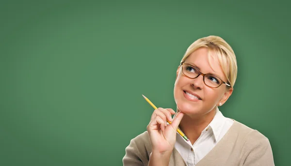 Attraktive junge Frau mit Bleistift vor leerer Kreidetafel — Stockfoto