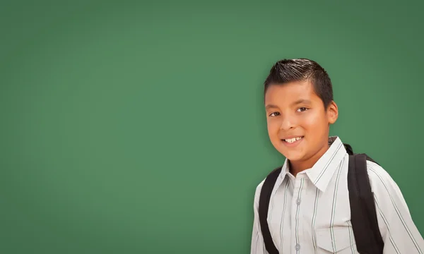 Bonito menino hispânico na frente da placa de giz em branco — Fotografia de Stock