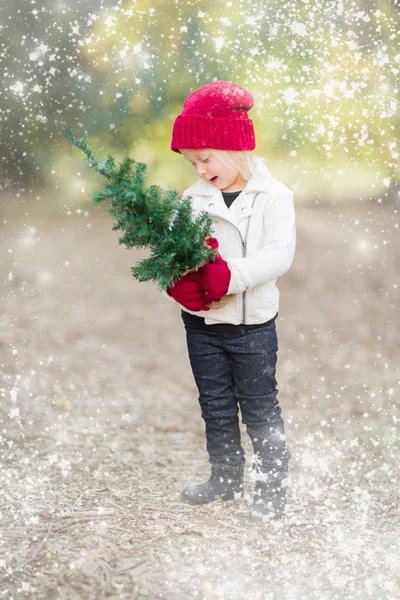 Baby Girl In Mittens Holding Small Christmas Tree with Snow Effe — Stock Photo, Image