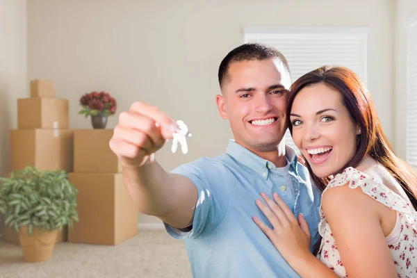 Mladí vojenské pár s klíče od domu v prázdné místnosti s zabaleno — Stock fotografie