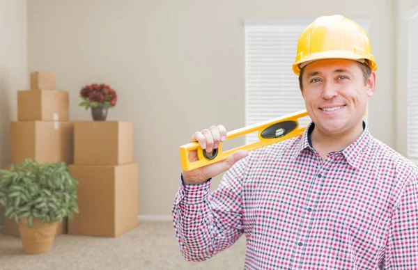 Trabajador de construcción masculino en la habitación con cajas móviles que sostienen el nivel —  Fotos de Stock