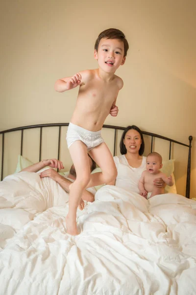 Mixed Race Chinese and Caucasian Boy Jumping In Bed with His Fam — Stock Photo, Image