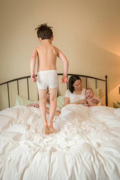 Mixed Race Chinese and Caucasian Boy Jumping In Bed with His Fam — Stock Photo, Image