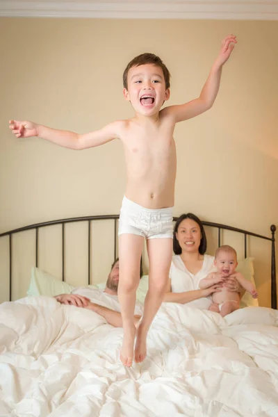 Blandad ras kinesiska och kaukasiska pojke hoppar i säng med hans Fam — Stockfoto